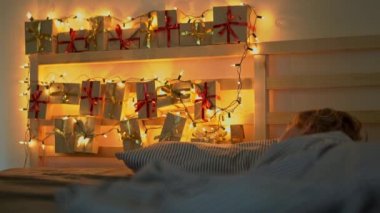 küçük bir çocuk yatakta bir geliş takvimi ile uyku Noel ışıkları ile hafifletmek onun yatağın bir arka parlar. Noel ve yeni yıl konsepti için hazırlanıyor. Advent takvim kavramı