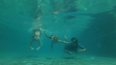 Bir yüzme havuzunda mutlu bir aile dalış Slowmotion sualtı çekim. Sağlıklı yaşam tarzı, aktif ebeveynler