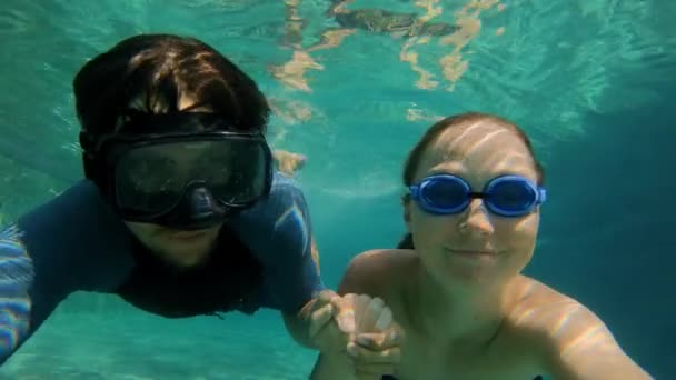 Slowmotion plan sous-marin d'un couple heureux femme et homme plonger dans une piscine. Mode de vie sain, personnes actives — Video