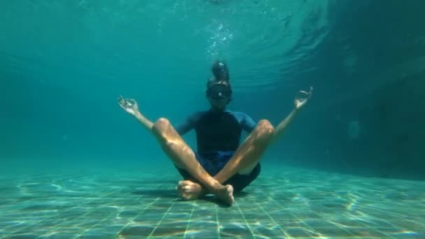 Zeitlupen-Unterwasseraufnahme eines jungen Mannes in Yoga-Pose, der auf dem Boden eines Swimmingpools meditiert. das Konzept der vollständigen Trennung — Stockvideo
