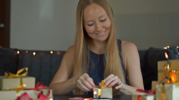 Una giovane donna che fa i regali. Regalo avvolto in carta artigianale con un nastro rosso e oro per Natale o Capodanno. Donna fa un calendario dell'avvento per i suoi figli — Video Stock