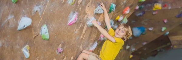 Niño pequeño escalando una pared de roca con botas especiales. BANNER interior, FORMATO LARGO —  Fotos de Stock