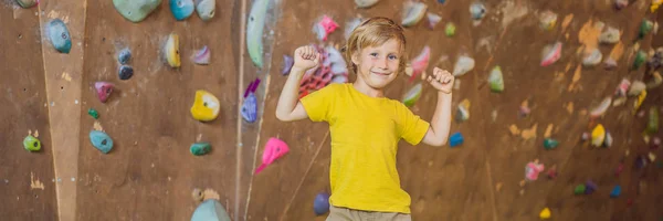 Little boy climbing a rock wall in special boots. indoor BANNER, LONG FORMAT — Stock Photo, Image