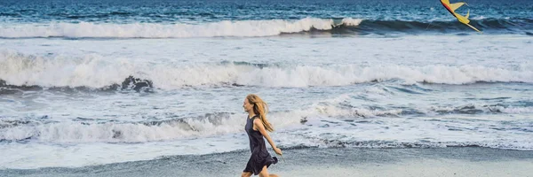 En ung kvinna lanserar en drake på stranden. Dröm, ambitioner, framtidsplaner banner, lång format — Stockfoto