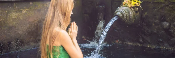 Femme dans le temple de l'eau de source sainte à Bali. Le complexe du temple se compose d'un petirtaan ou structure de baignade, célèbre pour sa bannière d'eau de source sainte, FORMAT LONG — Photo