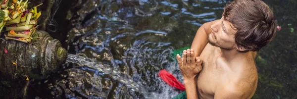 Человек в храме святой родниковой воды на Бали. Соблазнительное соединение состоит из petirtaan или купального сооружения, известного своей святой родниковой водой BANNER, LONG FORMAT — стоковое фото