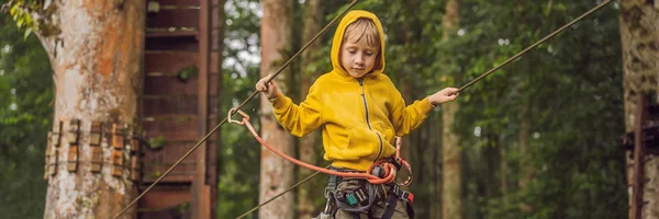 Kisfiú egy kötélen parkban. Aktív testi kikapcsolódás a gyermek friss levegőn a parkban. Gyermekek képzése transzparens, hosszú formátum — Stock Fotó