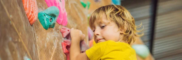 Little boy climbing a rock wall in special boots. indoor BANNER, LONG FORMAT — Stock Photo, Image