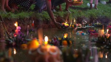 kişi yüzen krathongs dolu bir suda yanan bir mum ile bir Krathong koyar. Geleneksel bir Tayland tatili kutluyor-Loy Krathong