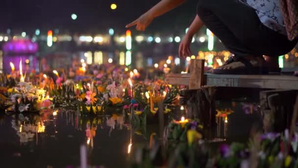 Persona mette un krathong con una candela accesa in un'acqua piena di krathongs galleggianti. Festeggiamo una tradizionale festa thailandese - Loy Krathong — Video Stock