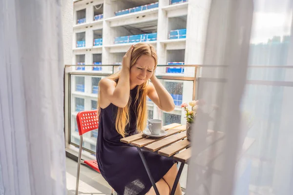 Ung kvinna på balkongen irriterade av byggnaden fungerar utanför. Brus koncept. Luftföroreningar från att bygga damm — Stockfoto