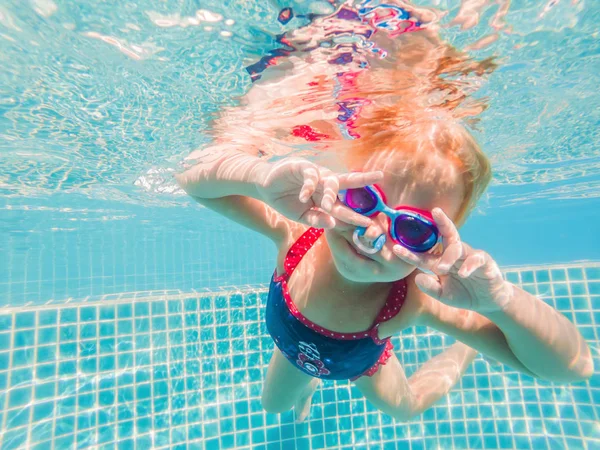 La niña en el parque acuático nadando bajo el agua y sonriendo — Foto de Stock