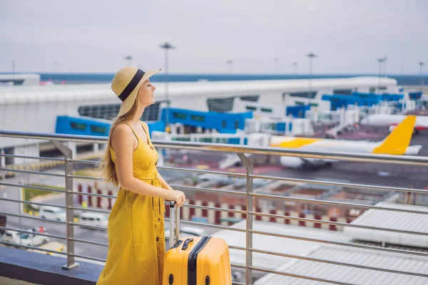 Beginn ihrer Reise. Schöne junge Frau im gelben Kleid und gelbem Koffer wartet auf ihren Flug — Stockfoto