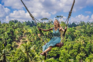 Endonezya'nın Bali adasının orman yağmur ormanlarında sallanan genç bir kadın. Tropik lerde salıncak. Swings - Bali trendi