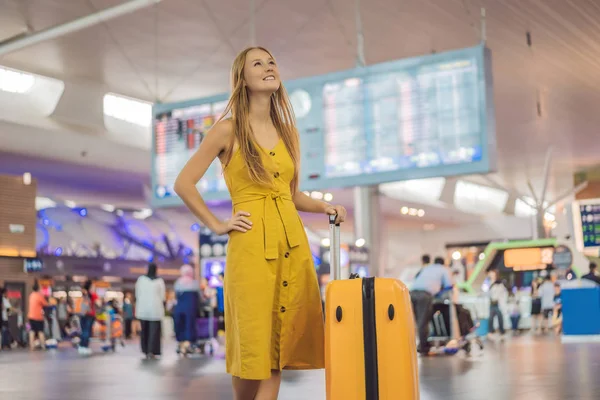 Beginn ihrer Reise. Schöne junge Frau im gelben Kleid und gelbem Koffer wartet auf ihren Flug — Stockfoto