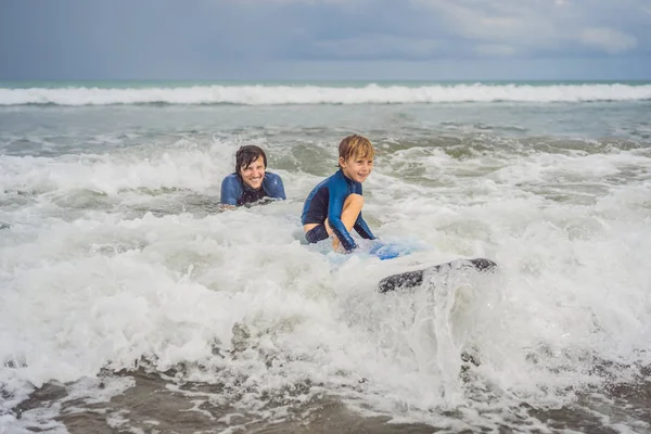 Padre o istruttore che insegna a suo figlio di 5 anni come navigare in mare in vacanza o in vacanza. Viaggio e sport con bambini concetto. Lezione di surf per bambini — Foto Stock