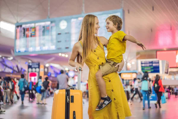 Familie vor dem Abflug am Flughafen. Mutter und Sohn warten am Abfluggate des modernen internationalen Terminals darauf, an Bord zu gehen. Reisen und Fliegen mit Kindern. Mutter mit Kind steigt in Flugzeug. gelbe Familie — Stockfoto