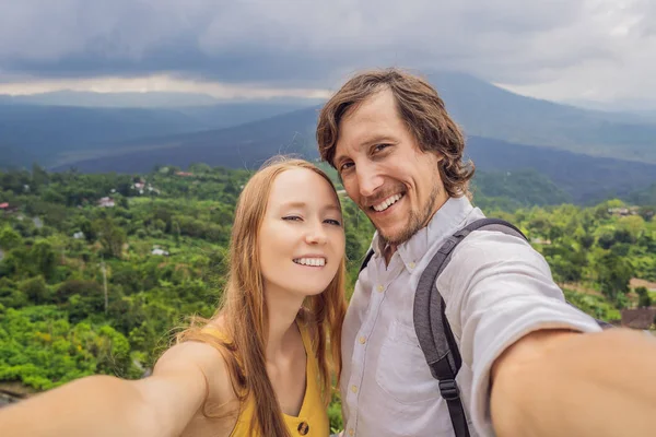 Hombre y mujer haciendo selfie en el fondo del volcán Batur y la vista de la montaña Agung en la mañana desde Kintamani, Bali, Indonesia — Foto de Stock