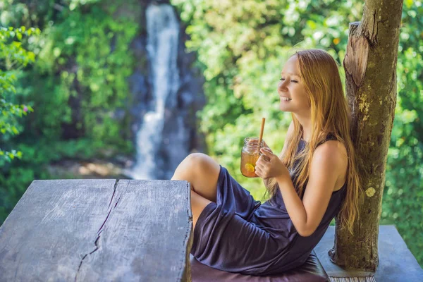 Zbliżenie portret obraz pięknej kobiety picia herbaty lodu z poczuciem szczęśliwego w zielonej przyrodzie i wodospad ogród tle — Zdjęcie stockowe