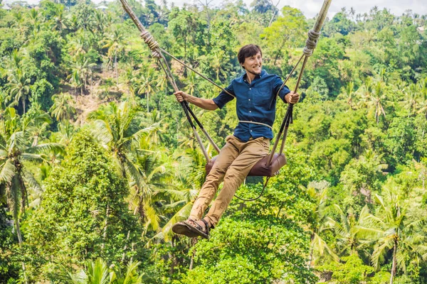 Молодой человек, качающийся в джунглях тропического леса острова Бали, Индонезия. Качели в тропиках. Качели - тренд Бали — стоковое фото