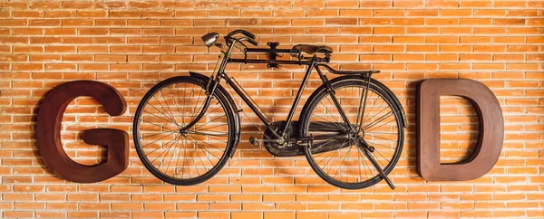 Inscription GOOD written with letters and a bicycle on the background of a brick wall. Eco-friendly transport concept. Moving from car to bike