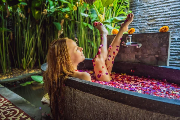 Attraente Giovane donna in bagno con petali di fiori tropicali e oli aromatici. Trattamenti termali per il ringiovanimento cutaneo. Donna seducente nel salone Spa. Ragazza rilassante nella vasca da bagno con petali di fiori. Lusso — Foto Stock