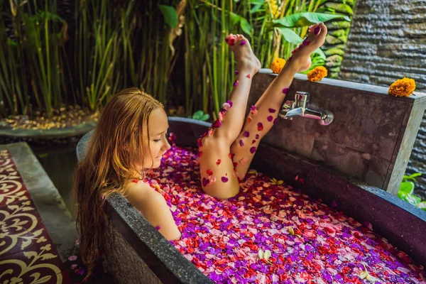 Mulher jovem atraente em banho com pétalas de flores tropicais e óleos de aroma. Tratamentos de spa para rejuvenescimento da pele. Uma mulher sedutora no salão de Spa. Menina relaxante na banheira com pétalas de flores. Luxo — Fotografia de Stock