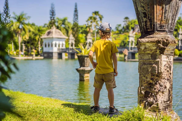 Fiatal fiú a Water Palace Soekasada Taman Ujung romok Bali szigetén Indonéziában. Csodálatos régi építészet. Utazás és nyaralás háttérrel. Utazótáska-val Kids fogalom. Gyerekbarát helyek — Stock Fotó