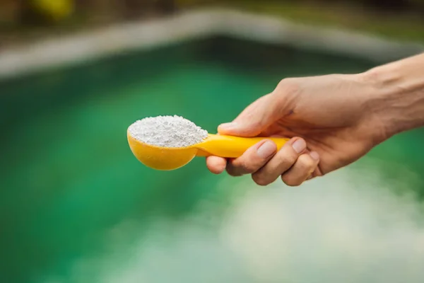 Hand håller Klorineför vatten i poolen — Stockfoto