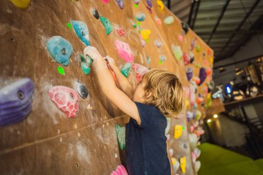 Küçük çocuk özel botlar içinde bir kaya duvarına tırmanıyor. Kapalı