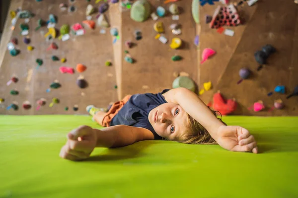 Boy resting after climbing a rock wall indoor — Stock Photo, Image