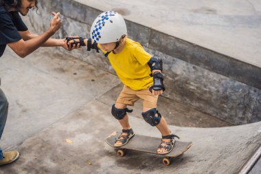 Atletik çocuk bir paten parkı bir eğitmen ile kaykay öğrenir. Çocuk eğitimi, spor