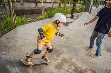 Atletik çocuk bir paten parkı bir eğitmen ile kaykay öğrenir. Çocuk eğitimi, spor