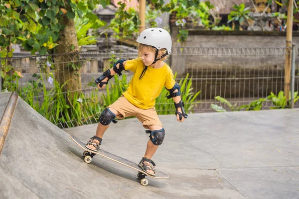 Спортсменка в шоломі і колінах вчиться кататися на скейтборді в ковзанярському парку. Дитяча освіта, спорт — стокове фото