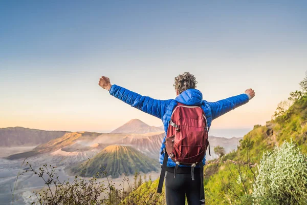 Young man meets the sunrise at the Bromo Tengger Semeru National Park on the Java Island, Indonesia. He enjoys magnificent view on the Bromo or Gunung Bromo on Indonesian, Semeru and other volcanoes — Stock Photo, Image