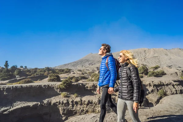 Young couple man and woman visit the Bromo volcano at the Tengger Semeru National Park on the Java Island, Indonesia. They enjoy magnificent view on the Bromo or Gunung Bromo on Indonesian, Semeru and — Stock Photo, Image