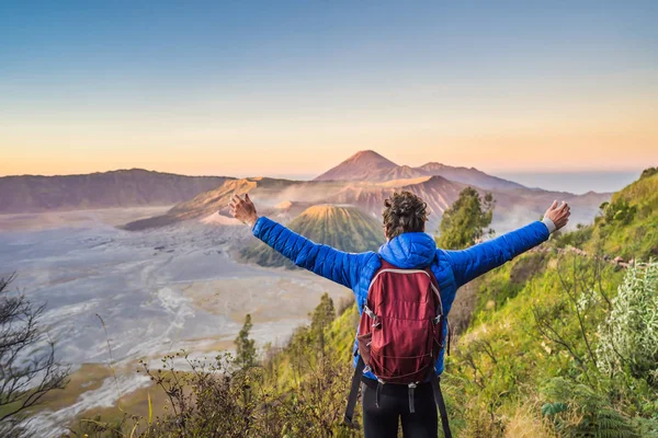 Young man meets the sunrise at the Bromo Tengger Semeru National Park on the Java Island, Indonesia. He enjoys magnificent view on the Bromo or Gunung Bromo on Indonesian, Semeru and other volcanoes — Stock Photo, Image