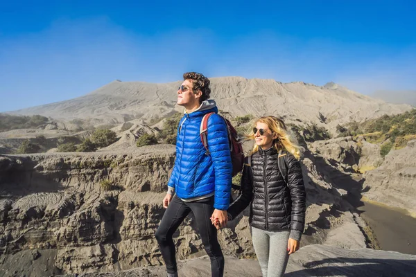 Young couple man and woman visit the Bromo volcano at the Tengger Semeru National Park on the Java Island, Indonesia. They enjoy magnificent view on the Bromo or Gunung Bromo on Indonesian, Semeru and — Stock Photo, Image