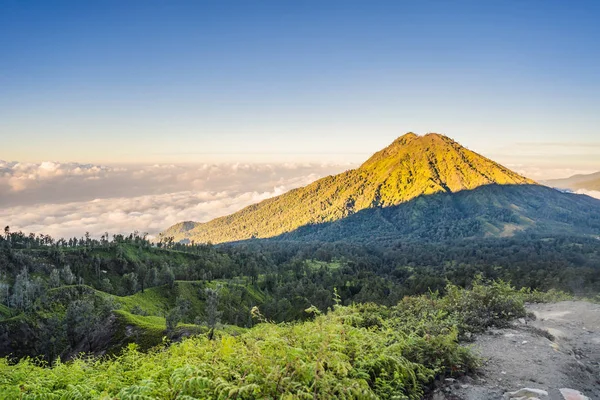 Великолепные виды на зеленые горы с горной дороги, ведущей к вулкану Иволкано или Кава-Иль на индонезийском языке. Известный вулкан, содержащий самое большое в мире кислотное озеро и — стоковое фото