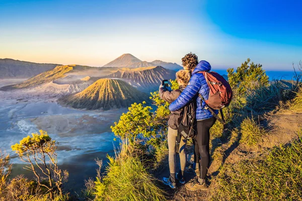 Genç çift erkek ve kadın Java Adası'nda Bromo Tengger Semeru Milli Parkı'nda gün doğumu karşılamak, Endonezya. Onlar Bromo veya Gunung Bromo Endonezya, Semeru ve muhteşem görünümü zevk — Stok fotoğraf