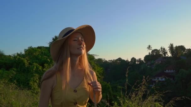 Super SlowMotion shot van een jonge vrouw in een gele jurk wandelen tijdens zonsondergang op de Campuhan Ridge Walk of schilders loopbrug in Ubud. Travell bestemmingen op Bali. Travell naar Bali concept. — Stockvideo