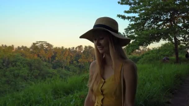 Una mujer joven con un vestido amarillo caminando en la colina de Campuhan o pintores pasarela en Ubud. Viajar destinos en Bali. Viajar al concepto de Bali . — Vídeo de stock