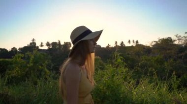 Campuhan sırt yürüyüş veya Ressamlar Ubud yürüyüş gün batımı sırasında yürüyen sarı elbiseli genç bir kadının Süper slowmotion çekim. Bali'deki seyahat noktaları. Travell bali kavramı.