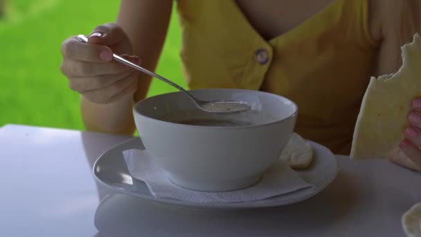 Closeup shot of a young woman enjoing traditional East Asian meals in a cafe with a rice field at a background. Travel to Bali concept. — Stock Video