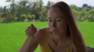 Arka planda pirinç tarlası olan bir kafede geleneksel Doğu Asya yemeklerini sevinci yle çeken genç bir kadının yakın çekim fotoğrafı. Bali konseptine seyahat.