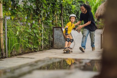 Atletik çocuk bir kaykay parkta Asya eğitmen ile kaykay öğrenir. Çocuk eğitimi, spor. Irk çeşitliliği