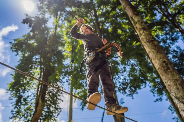 Un niño en un parque de cuerdas. Recreación física activa del niño al aire libre en el parque. Formación para niños —  Fotos de Stock