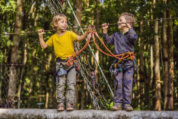 Два маленьких мальчика в веревочном парке. Активный физический отдых ребенка на свежем воздухе в парке. Обучение детей — стоковое фото