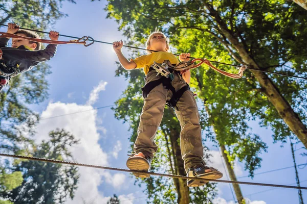 Dois rapazinhos num parque de cordas. Recreação física ativa da criança ao ar livre no parque. Treinamento para crianças — Fotografia de Stock
