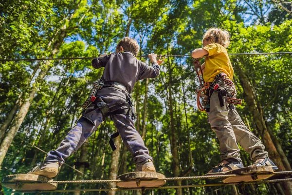 Dois rapazinhos num parque de cordas. Recreação física ativa da criança ao ar livre no parque. Treinamento para crianças — Fotografia de Stock
